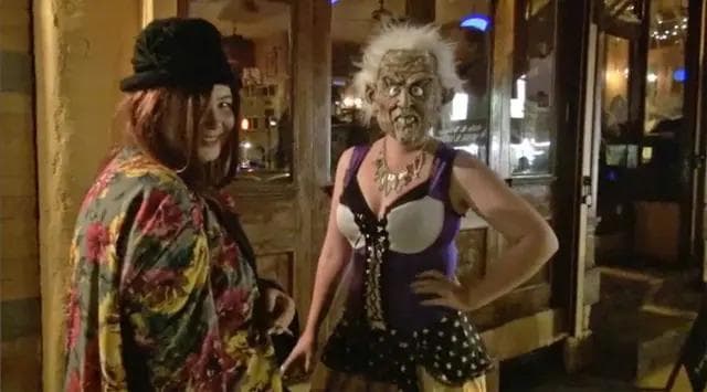 two women in costume, one with a grotesque mask