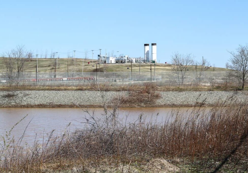 A flare station across the water in winter light with fences.